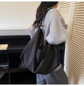 Detail der schwarzen Canvas-Hobo-Tasche mit braunen Holzperlen-Akzenten am Schultergurt