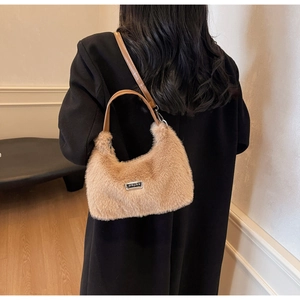 Detail of soft faux fur shoulder bag in apricot with leather strap and metal plate