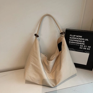 Detailansicht der cremefarbenen Canvas-Tasche mit dekorativen dunklen Holzperlen am Träger