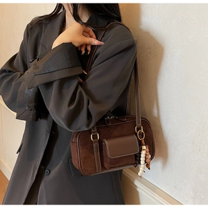Detail of dark brown suede Boston bag with contrast white stitching and wooden bead charm