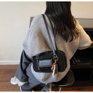 Detail of black suede Boston bag with colorful bead tassel and metallic zipper