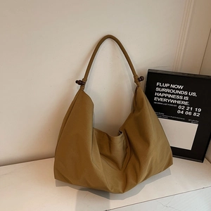 Detail der khakifarbene Canvas-Hobo-Tasche mit dunklen Holzperlen und weichen Falten