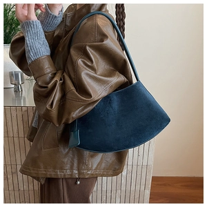 Détail d'un sac bandoulière en daim bleu marine porté avec une veste en cuir d'automne