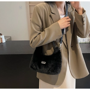 Detail of black faux fur plush crossbody bag with leather strap and silver metal logo plate