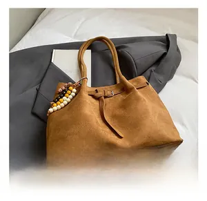 Detaillierte Nahaufnahme der braunen Wildledertasche mit Zierriemen und Ethno-Perlen