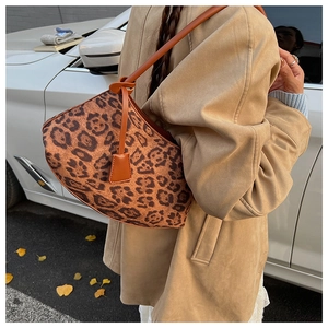 Détail du sac à bandoulière léopard avec lanière en cuir marron dans un décor d'automne