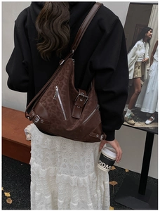 Detail view of brown leopard print suede tote bag with metallic zippers on shoulder
