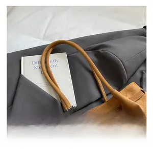 Detail der braunen Wildleder-Einkaufstasche mit Leder-Schnallenriemen und Perlenanhänger