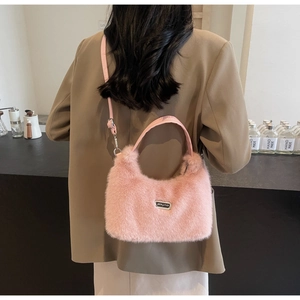 Detail view of pink faux fur crossbody bag with leather handles shown in a cafe setting