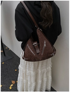 Detail of a brown leopard print shoulder bag with metallic zippers on a crossbody strap