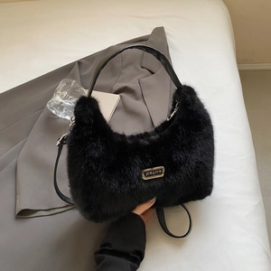 Detail of black faux fur shoulder bag with gold metal logo on a grey suit jacket