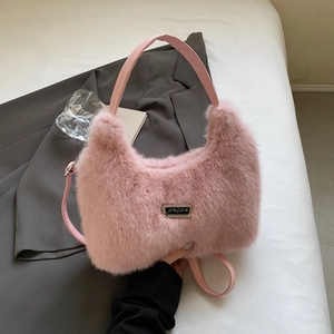 Detail shot of plush pink faux fur bag with leather straps and silver metal logo tag