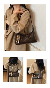 Détail du sac sous le bras en cuir marron vintage avec un charmant pendentif en perles
