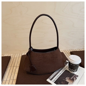 Détail du sac bandoulière en daim marron foncé avec étiquette en cuir et zip
