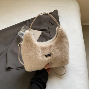 Detail showing plush beige faux fur texture and branded metal plate on hobo handbag