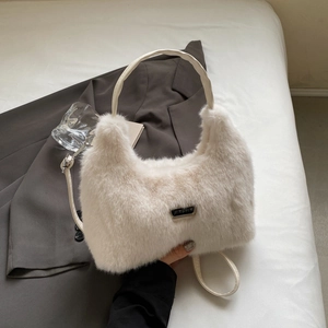 Close-up of cream faux fur texture and black metal logo on a plush shoulder bag