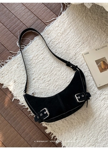 Détail du sac croissant noir avec boucles argentées sur tissu mat texturé
