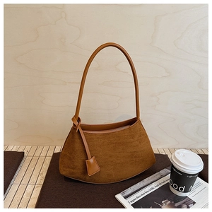 Détail d'un sac à bandoulière en daim marron vintage avec un design rétro en demi-lune