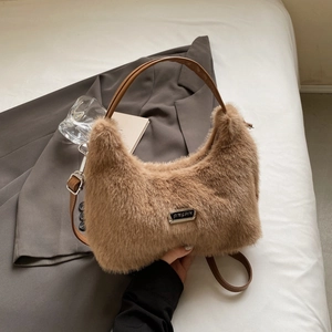 Detailed view of plush faux fur handbag with leather handle and metal logo plate