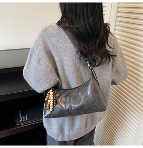 Vue détaillée du sac hobo vintage gris avec surpiqûres et breloque en perles de bois
