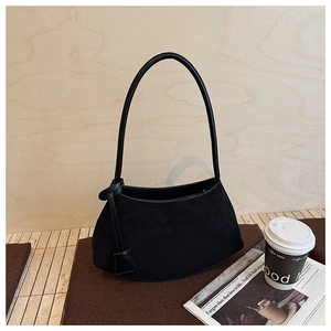 Détail du sac à bandoulière en daim noir mat avec breloque à nœud et design incurvé élégant