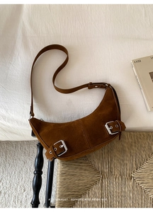 Gros plan du sac demi-lune en daim marron avec boucles argentées et bandoulière réglable