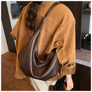 Detail view of a large vintage brown soft leather hobo bag worn as a shoulder bag