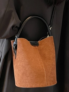 Brown matte suede bucket bag with black leather handle shown on model in a 2025 style