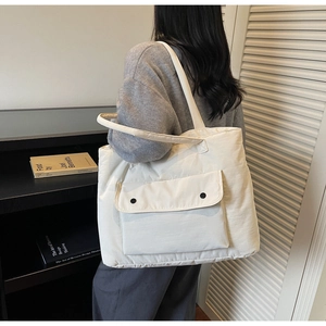 Quilted tote bag detail showing large capacity and cream fabric with black snap pocket