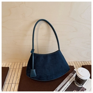 Détail du sac hobo en daim bleu marine posé dans un décor de style de vie urbain chic