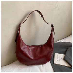 Detail of dark red crescent shoulder bag featuring premium pebbled texture and stitching
