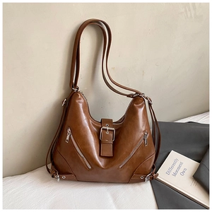 Detail of a brown vintage faux leather tote bag with large metal buckle and dual zipper pockets