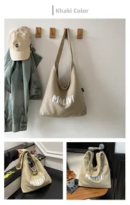 Close-up of khaki checked canvas tote bag with white MALIVI lettering in a casual setting