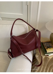 Detail of burgundy pebbled leather tote bag with top zipper and elegant side buckle detail
