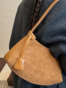 Sac à bandoulière vintage en daim marron à silhouette courbée porté sur un manteau en laine