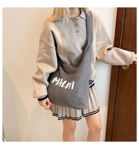 Close-up of houndstooth canvas crossbody bag with MACN print worn with a stylish outfit