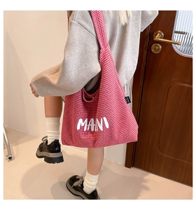 Side view of red gingham canvas tote bag with MANI lettering on minimalist background