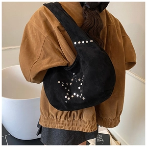 Primer plano del bolso hobo de ante negro con tachuelas de estrellas en una modelo