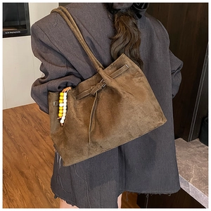 Detailansicht der Vintage-Wildledertasche mit dekorativen Holzperlen an einem Model