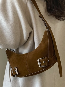 Sac hobo rétro en daim marron avec boucle métallique, porté par un mannequin en manteau
