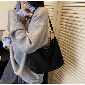 Dettaglio della borsa hobo nera minimalista con finiture dorate e accenti di manico intrecciato