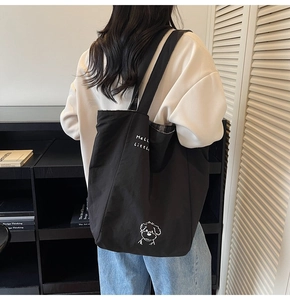 Close-up of black canvas tote bag with Hello Little text and cute puppy embroidery
