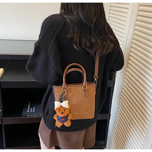 Detail of brown vintage crossbody bucket bag with a cute bear plush charm decoration