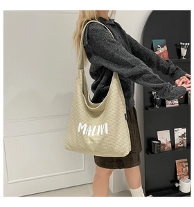 Detail view of the green checkered canvas tote bag with MALINI white artistic lettering