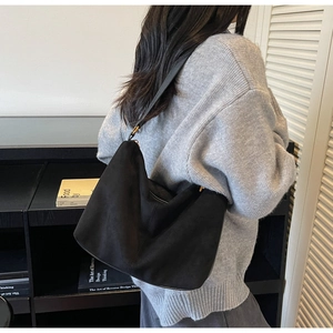 Dettaglio della borsa a spalla minimalista in camoscio nero con tracolla in pelle e cerniera