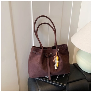 Detailansicht der braunen Wildleder-Tragetasche mit Perlenanhänger auf Vintage-Hintergrund