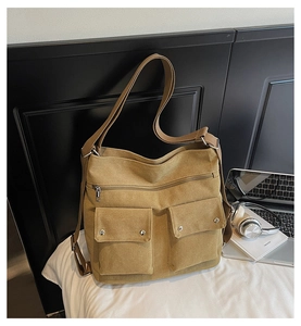 Detail of khaki canvas bag with double front pockets, adjustable strap and zipper closure