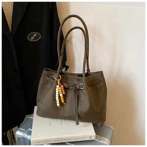Detail der dunkelbraunen Wildleder-Tragetasche mit Metallschnalle und Perlenquaste