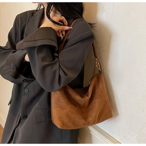 Dettaglio della borsa a spalla in pelle scamosciata marrone con catena in metallo