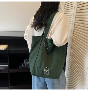 Deep green canvas tote bag with dog print shown in a lifestyle home setting for women